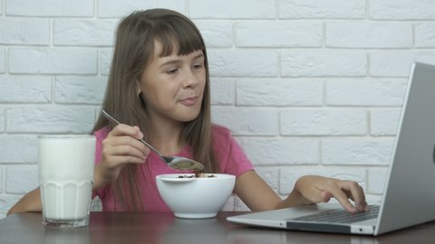 Breakfast with internet. Teen girl eats and browses social networks in a laptop.