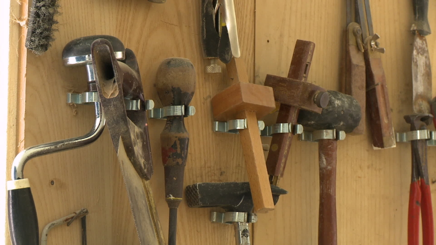 Steady, medium close up shot of tools on a wall in a shed.