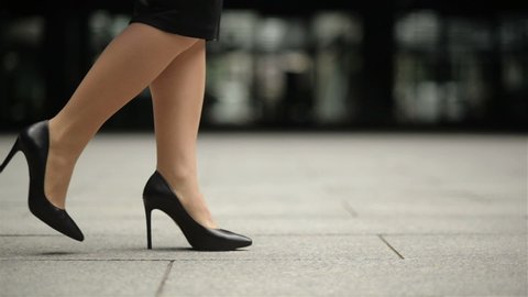 Feet Of Young Business Woman In High-Heeled Footwear Going In City. Businesswoman Legs In High-Heeled Shoes Walking Near Office After Work. Slow Motion.