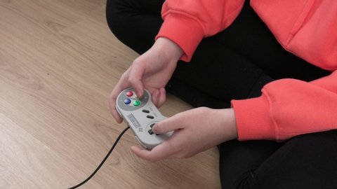 Yekaterinburg, Russia - November 4, 2019: Teenager holding Super NES (Super Famicom) Nintendo game pad. Super Nintendo was very popular game console in 90's