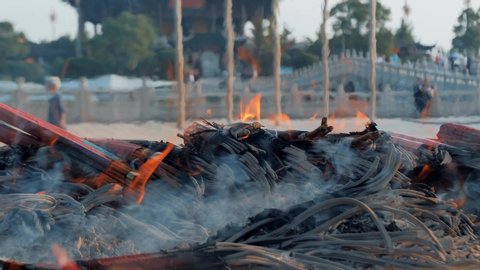 Incense sticks are burning slowly in the burner of a chinese temple. Slow motion shot.
