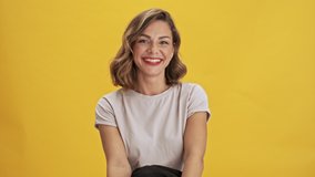 Beautiful young woman with red lips looks happy, laughing and smiling while looking at the camera over yellow background isolated