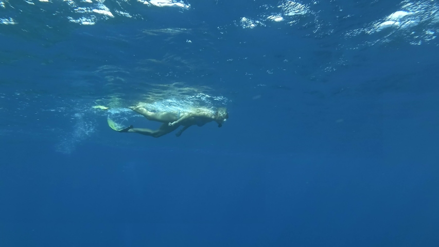 Woman snorkeling in blue water. Woman with mask and fins swims in the blue water of the ocean. Underwater shot, Red Sea, Egupt