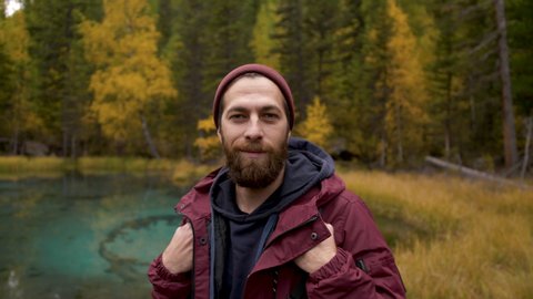 Portrait of Young Smiling Man Standing in Forest. Traveling Concept People in Nature. One 30s Person Tourist Looking at Camera On the Background of Autumn Landscape Closeup. Hiker Journey in Wildlife