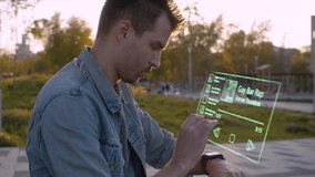 Portrait of a man in the city park using transparent futuristic device. Video and animation