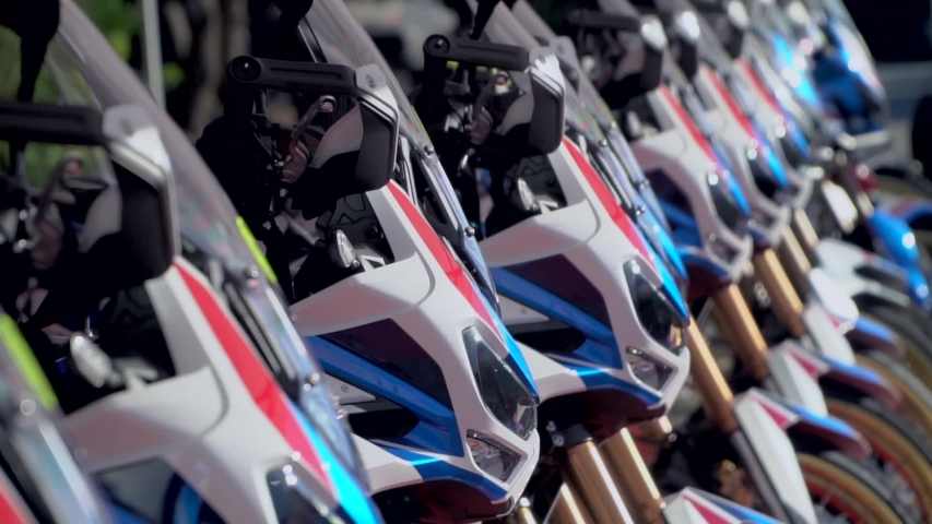 Close-up. New models of tourist motorcycles stand in a row in the sun. The front of the motorcycle. wheel and steering wheel. Legendary model. Parked motor. Before the start of the rally.