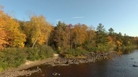 Cool slow moving aerial video of rocky river in fall with blue sky