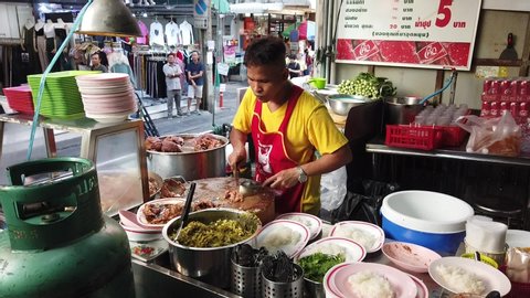Bangkok / Thailand - 28 October 2019 Famous food in Bangkok Pratunam Soi 19 Wanton Mee and Braised pork. Person preparing braised pork into smaller portion served onto white rice