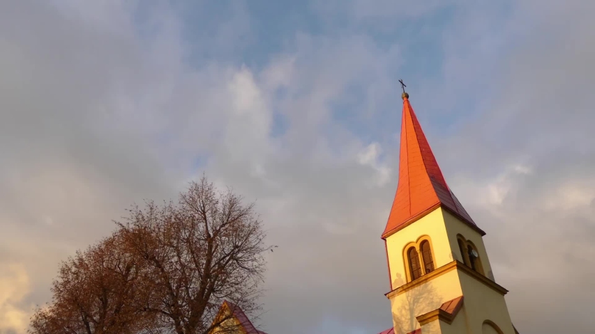 Little beautiful girl in red jacket walks near Church St. Stefan Uhorskeho, Janovce-Cencice, Slovakia.