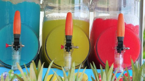 Freezing and mixing machines for making ice slushy drinks containing blue, yellow and red slush. Cold colorful frozen sugar juice.