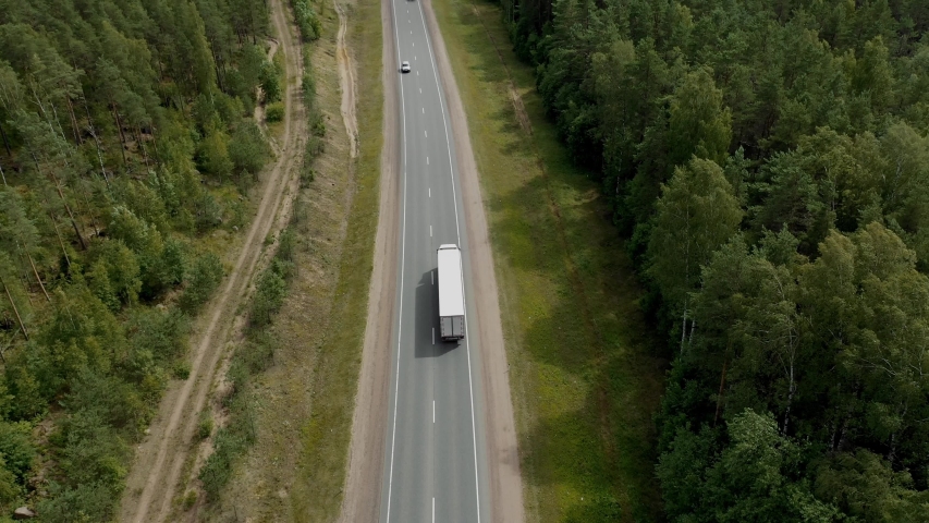 Aerial Top View of White Truck with Cargo Semi Trailer Moving on Road in Direction f Loading Warehouse Area. Royalty-Free Stock Footage #1040388560
