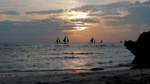Amazing colors of tropical sunset. Sail boats silhouettes floating on ocean horizon. Boracay island, Philippines summer vacation