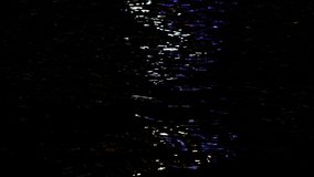 Dark sea water surface with colorful reflections of street seashore lightings at surface of black water. 4k video background.