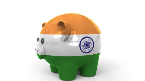 Coins fall into piggy bank painted with flag of India. National banking system or savings related conceptual 3D animation