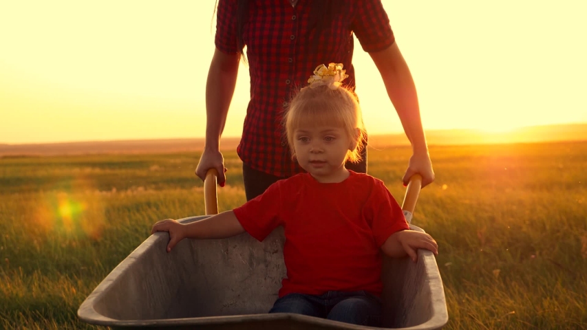 A young mother carries a little daughter on a cart. A happy family of farmers enjoy the wildlife.
