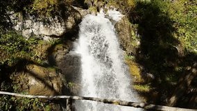A beautiful waterfall flows over rocky stones in the forest. Video with the sound of a waterfall.
