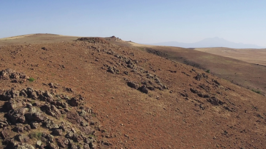 Arid red rocky hilly landscape / Summer sunny hot day / Aerial drone flight