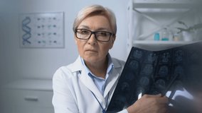 Patient watching mature female physician holding brain x-ray medical examination - Powered by Shutterstock - Get 15% off with code: PIKWIZARD15