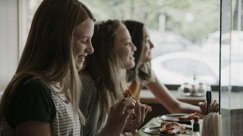 Close up of happy girls eating pizza slices in pizzeria / Provo, Utah, United States