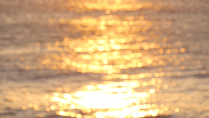 Golden glisten of sunlight reflects on the sunset sea surface. Sparkling sunlight over the calm water.  Royalty-Free Stock Footage #1040430569