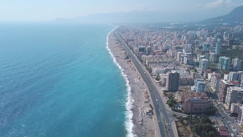 Aerial view of the beautiful coastline, modern hotels and sea blue water of Alanya in Turkey against blue sky in hot sunny day. Clip. Turkish summer resort