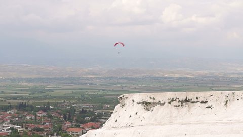 Vacation, extreme sports - red parachute over the sky with clouds. One women are flying in the blue sky using red parachute over the sea. Copy space. Sportsman flies paraglider in the sky. Paragliding