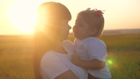 happy family outdoors in the park a mom and daughter slow motion video. little sunlight sunset girl hugs holds on hands daughter kisses mom lifestyle