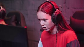 Young girl gamer in headphones, plays a video game, cyber sportsman at the game, communication between players.