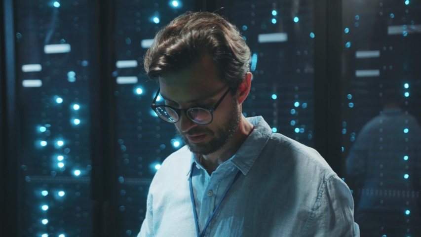IT technician in data center digital server room controlling work of rack server cabinets with a tablet. Professional server engineer at work. Royalty-Free Stock Footage #1040450081