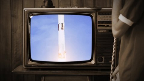 Young Man Speaking on Phone and Watching Historical Apollo 11 Launch on a Retro TV. Sepia Tone. Elements of this video furnished by NASA.