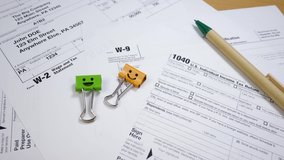Taxes form 1040, document for W-2 and W-9 form. Smiles Binder Clips and Pen. Report in The Internal Revenue Service (IRS) of The United States of America (USA). Federal government concept