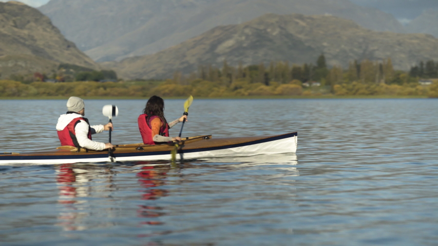 Active Caucasian couple ride in kayak spending their vacation together in Fall The Remarkables Lake Wakatipu Fjords New Zealand Royalty-Free Stock Footage #1040466944
