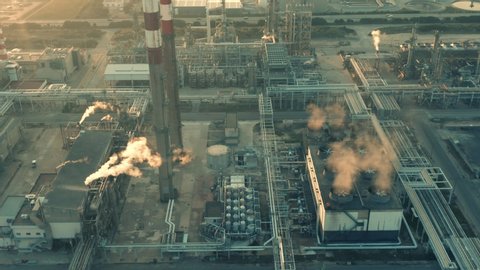 Aerial view of petrochemical oil refinery (refining complex) at sunset. Oil and gas tanks with smoking pipes on the plant (factory) 