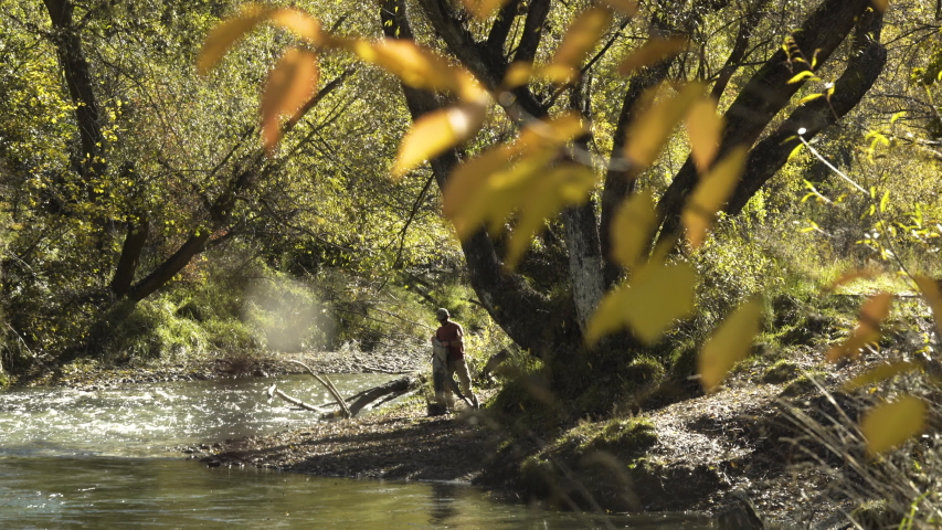 Young Caucasian male fly fisherman wearing fishing waders in Fall on the bank Kawarau River National Park Otago New Zealand