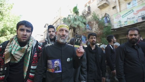 KARBALA, IRAQ - DEC 2015: An iranian pilgrim holds Revolutionary Guards leaders' pictures in Arbaeen. Every year, millions of Shiite muslims come from all over the world to Karbala to walk Arbaeen