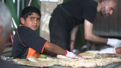 KARBALA, IRAQ - DEC 2015: "Servants" make hot fresh bread to feed pilgrims during Arbaeen Pilgrimage. Every year, millions of Shiite muslims come from all over the world to Karbala to walk Arbaeen