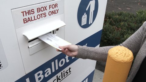 Person delivering voter's ballot to ballot box during election day.
