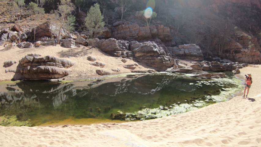 woman photographer in Ormiston Pound Walk, a circuit that follows the rocky slope into of pound and back along the gorge by main waterhole. West MacDonnell Range, Australia, Northern Territory