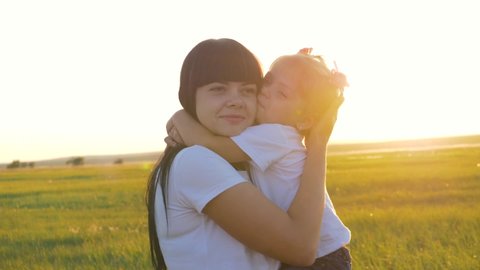 Loving mother and happy little daughter have fun outdoors at sunset. The family enjoys the weekend, nature and laughing.