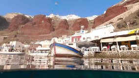 Underwater and sea level video of iconic port of Ammoudi below picturesque colourful village of Oia, Santorini island, Cyclades, Greece
