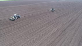 Stock video two tractors are driving across the field one after another, plowing and fluffing up the ground for further sowing of seeds. Sowing seeds, cultivation of agricultural land, 4k video
