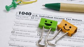 Smiles Binder Clips and Pen on 1040 Tax Form. Individual Income tax return document in United States