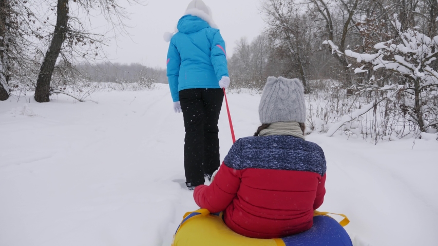 child and mother sledding in the snow. Daughter and mom play in the winter park on Christmas holidays. family winter vacation. happy childhood concept