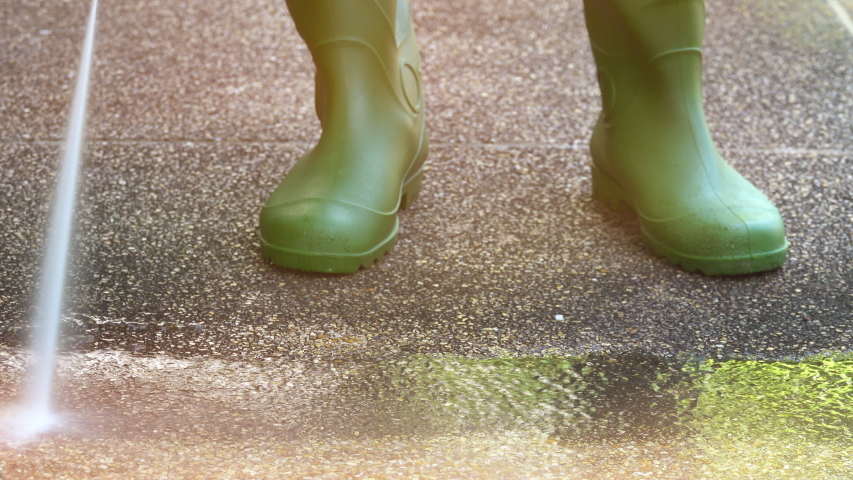 Worker cleaning pathway with high pressure washer splashing the dirt ,4K timelapse .
High pressure cleaning at sunrise,lower body with waterproof boots.
Professional cleaning services.
