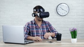 Man using virtual reality glasses moving arms sitting at desk in office