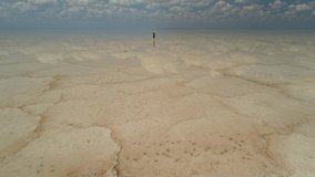 Drone forward woman walks on water unique salt lake Elton mirror surface reflection clouds horizon cinematic natural wonder Russia surface pattern cracks brine. Desert open space meditation relaxation - Powered by Shutterstock - Get 15% off with code: PIKWIZARD15