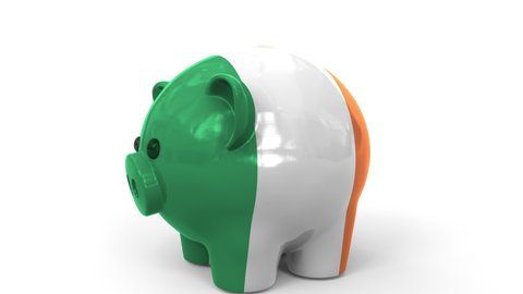 Coins fall into piggy bank painted with flag of the Republic of Ireland. National banking system or savings related conceptual 3D animation
