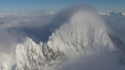snowy mountain peak surrounded by clouds