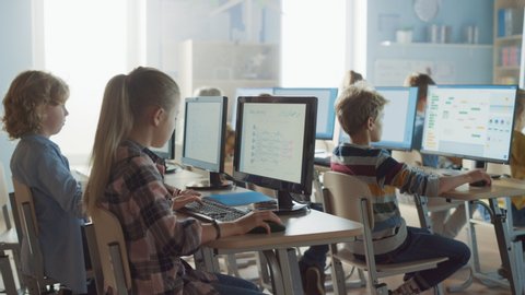 Elementary School Science Classroom: Teacher Educates Smart Little Schoolchildren who Work on Personal Computers, Learn Programming Language for Software Coding.Schoolchildren Getting Modern Education