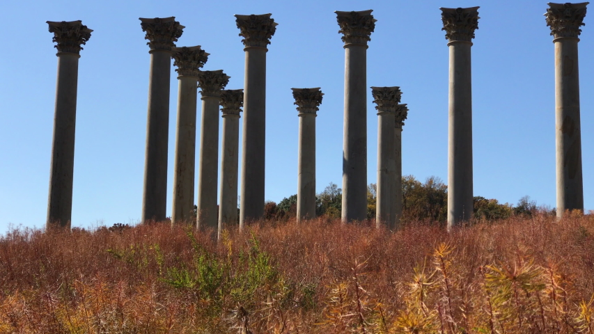 old columns at the  Arboretum in Washington DC, old greek columns with colorful orange and red flowers and plants in front of it. greek architecture. 
